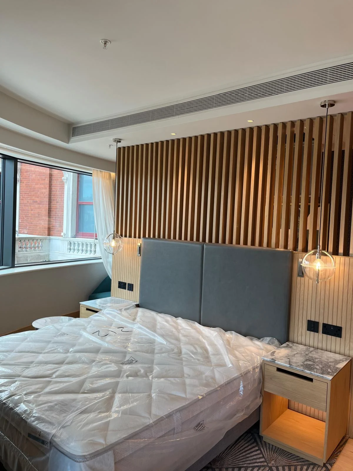 The Hyatt Regency Hotel — Guest room with timber headboard and pendant lights